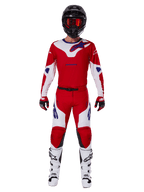 Motocrossförare i Alpinestars 2025 Racer Veil Gear Set, klarröd och vit tröja och byxor med blå detaljer, svart hjälm med röda goggles, vita stövlar och röda och svarta handskar, koordinerad outfit för terrängkörning
