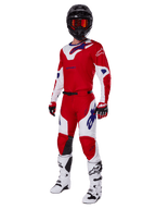 Alpinestars 2025 Racer Veil-ställ, motocrossutrustning, klarröd och vit med blå logotypdetaljer, bärs med en svart hjälm, röda handskar och vita stövlar, komplett skyddande utrustning för terrängkörning
