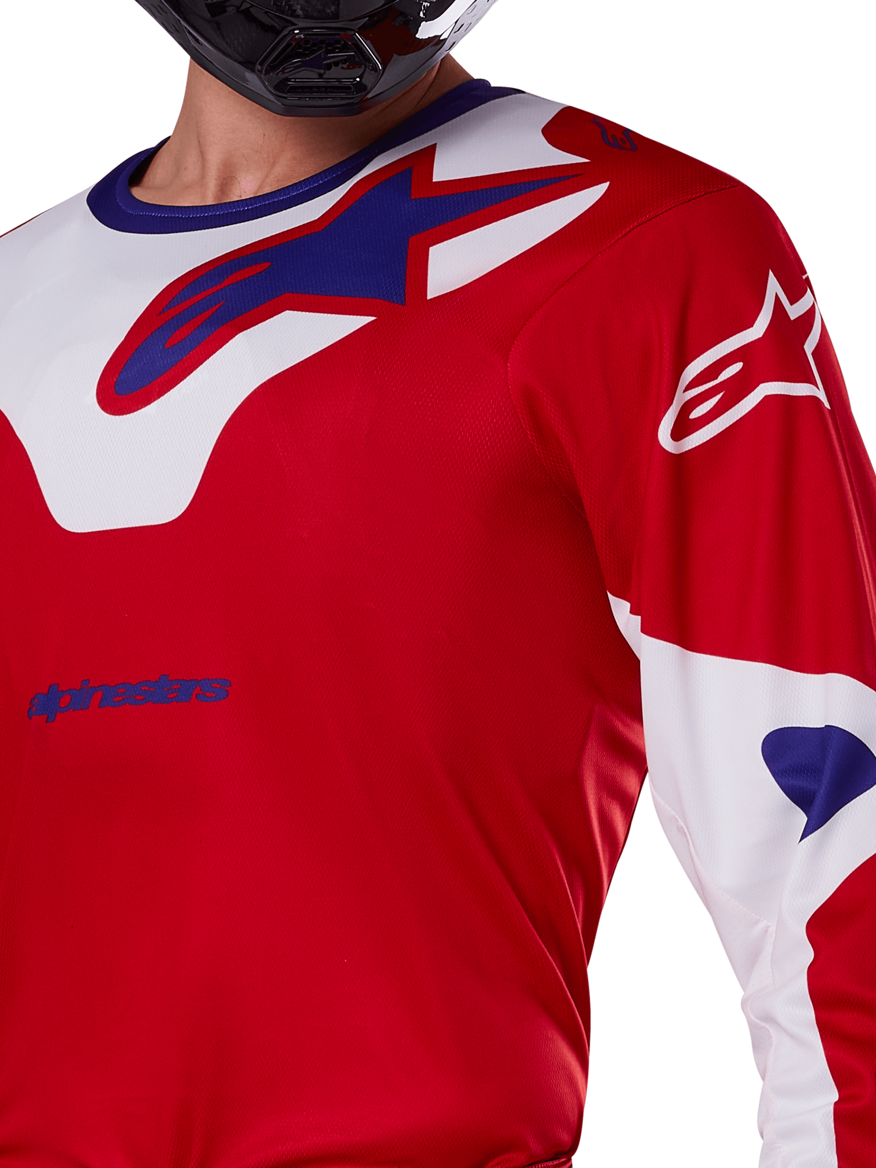 Alpinestars 2025 Racer Veil tröja, motocrosströja, klar röd och vit, närbild av överkropp och bröst, blå Alpinestars-logotyp på en vit kragpanel, röda ärmar med vita detaljer, bärs med en svart hjälm, tekniska kläder för terrängkörning
