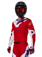 Alpinestars 2025 Racer Veil-ställ, motocrossförare klädd i röd, vit och blå racingtröja och byxor, svart hjälm med orangea spegelgoggles, röda och vita handskar, prestandautrustning för terrängkörning med tydlig profilering