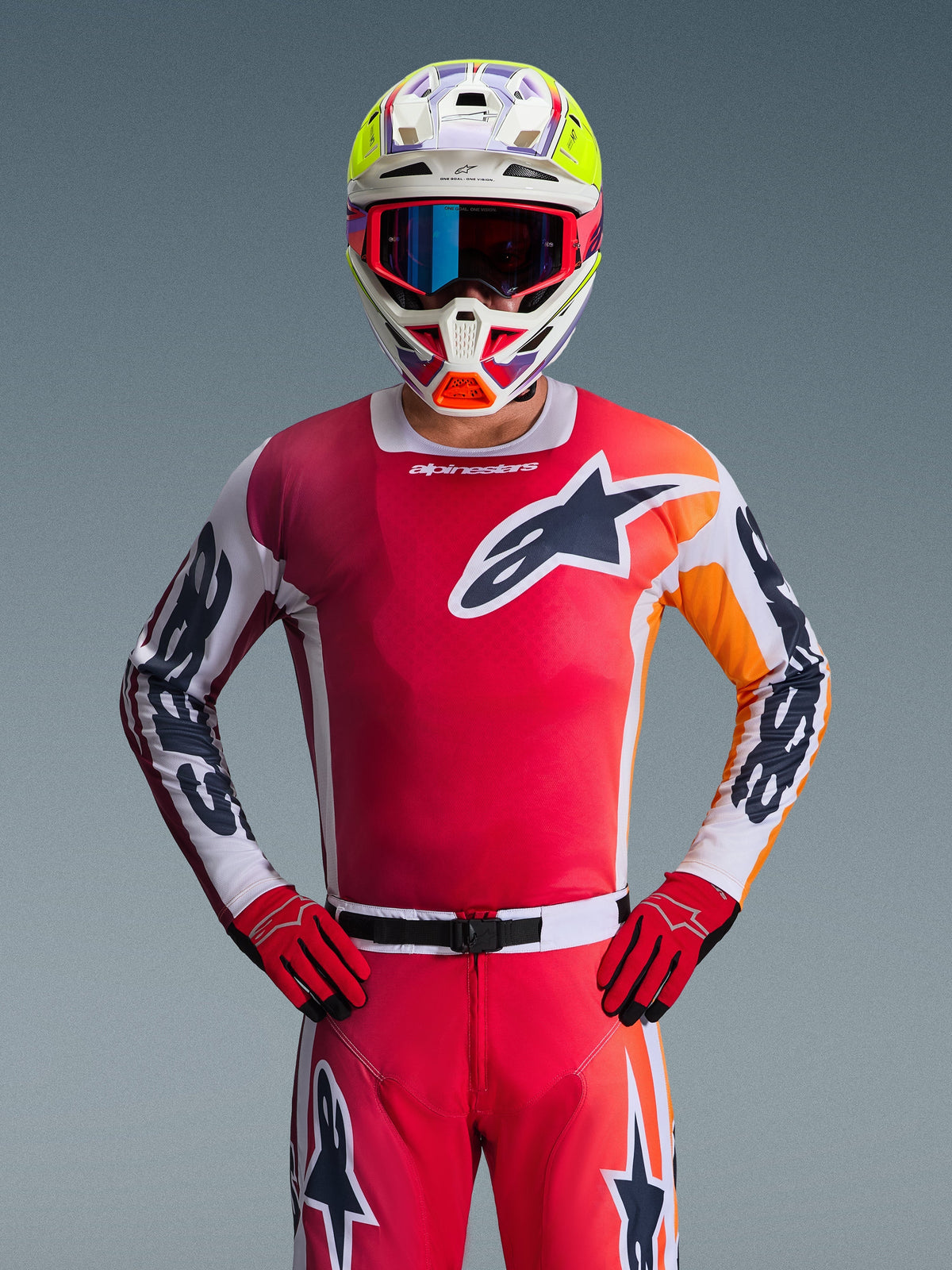 Alpinestars 2026 Racer Portl-tröja, röd motocrosströja, frontvy av en förare med matchande röda byxor och handskar, med en svart och vit stjärnlogotyp på bröstet och vita ärmar med svarta logotyper, kombinerat med en flerfärgad vit och gul hjälm, komplett professionell utrustning för offroad-racing.