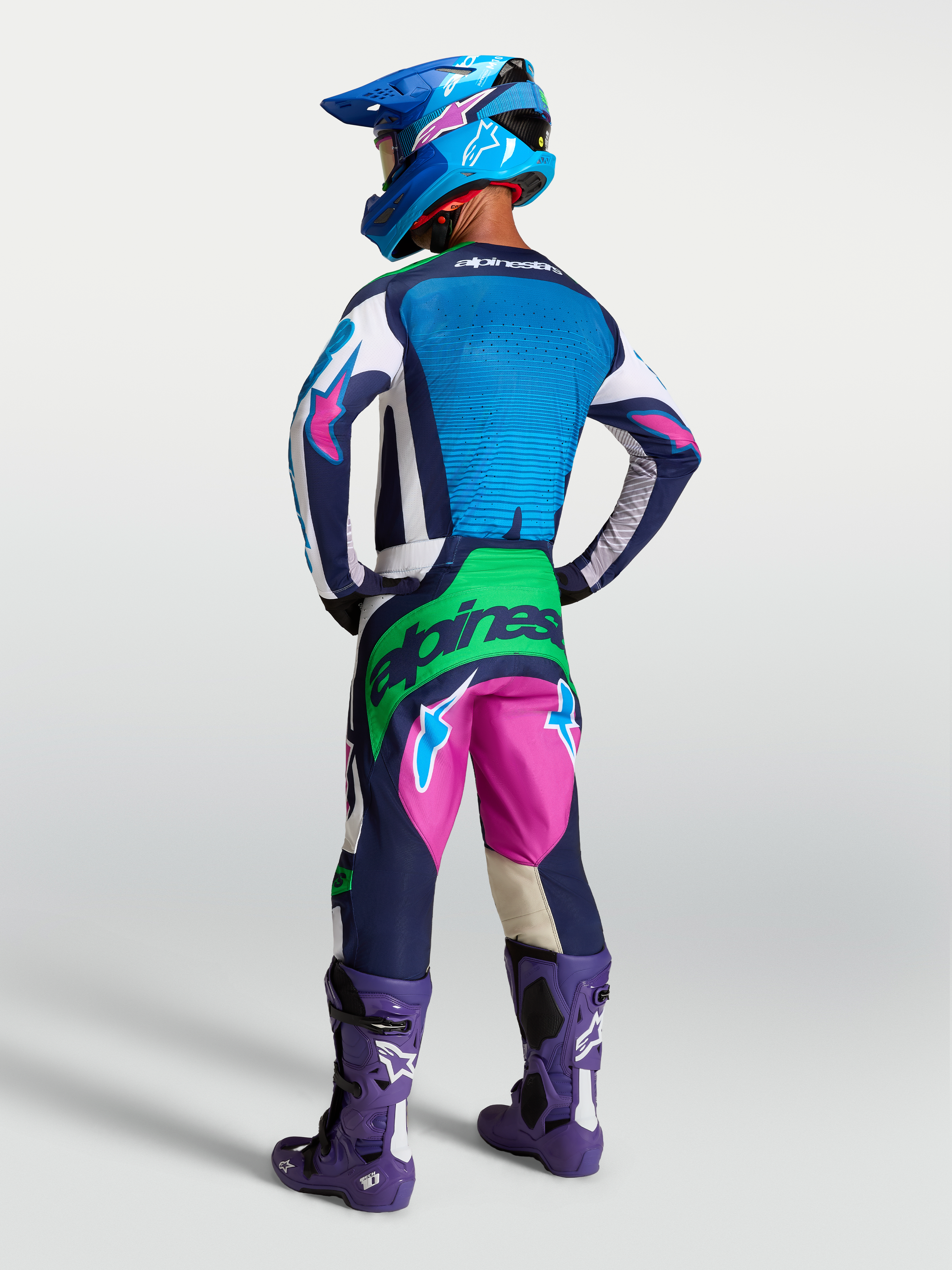 Alpinestars Techstar Maven tröja, blå och vit motocrosströja med atletisk passform, bärs av modell bakifrån med matchande utrustning för terrängkörning.