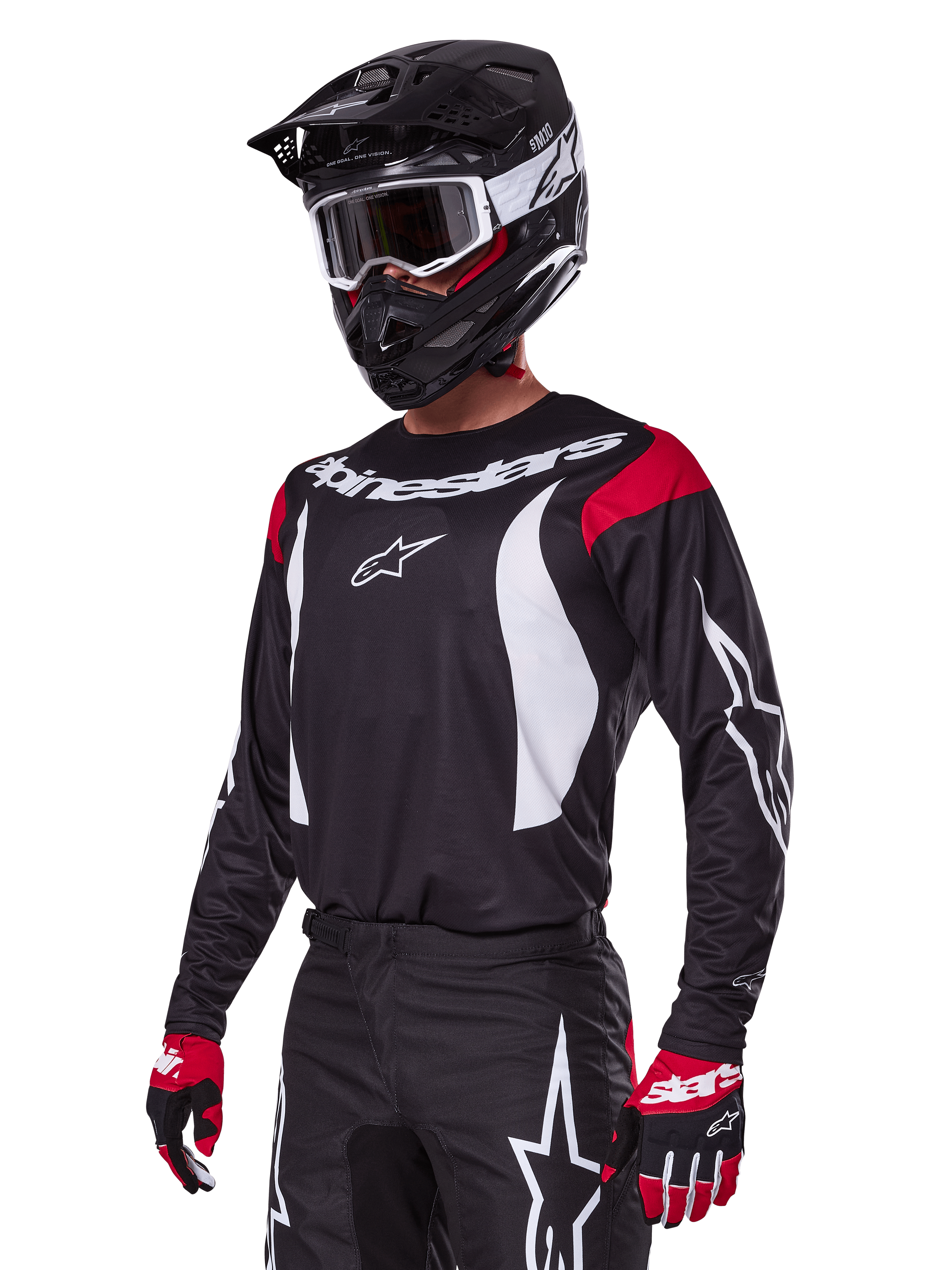 Motocrossförare i Alpinestars 2025 Fluid Haul utrustningsset, svart tröja med röda axelpaneler och vit grafik, matchande svarta byxor med vita stjärnlogotyper, röda och svarta handskar, svart hjälm med vita detaljer och goggles, koordinerad motocrossutrustning