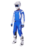 Motocrossförare som bär det kompletta utrustningssetet 2025 Fluid Haul, blå och vit tröja och byxor med Alpinestars-logotyper, vit hjälm med blå goggles, vita stövlar och blå handskar, koordinerad racingoutfit för offroad-motocross.
