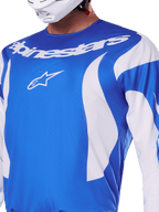 Alpinestars 2025 Fluid Haul Jersey, Blue and White, worn by a rider with a white helmet, featuring a white Alpinestars wordmark and A-star logo, athletic fit, lightweight moisture-wicking material for motocross and off-road riding