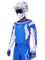 Motocrossförare som bär Alpinestars 2025 Fluid Haul utrustningsset i blått och vitt, blå tröja med vita detaljer, matchande blå byxor med stjärnlogotyper, vit hjälm med blå goggles, koordinerade blå och grå handskar, komplett racingoutfit för terrängkörning