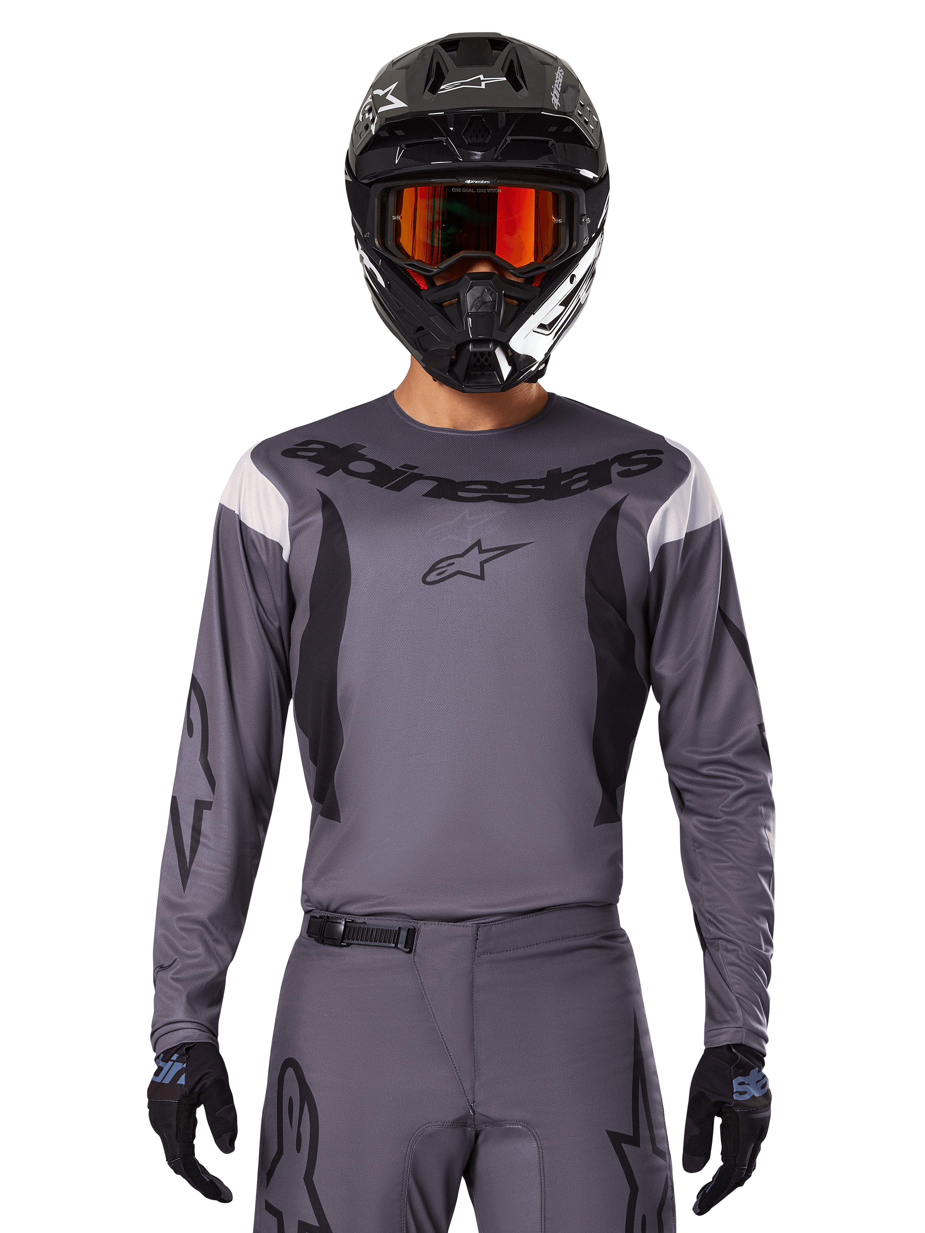 Motocrossförare i 2025 Fluid Haul-tröja och utrustningsset, grå med svarta och vita detaljer, långärmad design med framträdande logotyper, svart hjälm med orangea goggles och svarta handskar, koordinerad outfit för terrängkörning