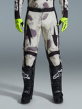 Alpinestars 2026 Racer Lahnd byxor, motocrossbyxor, Sand Camo-mönster med grå och lila abstrakt grafik, bärs med neongula handskar och svarta stövlar, svarta stjärnlogotyper på låren och ett svart midjebälte, hållbar racingutrustning för terrängkörning