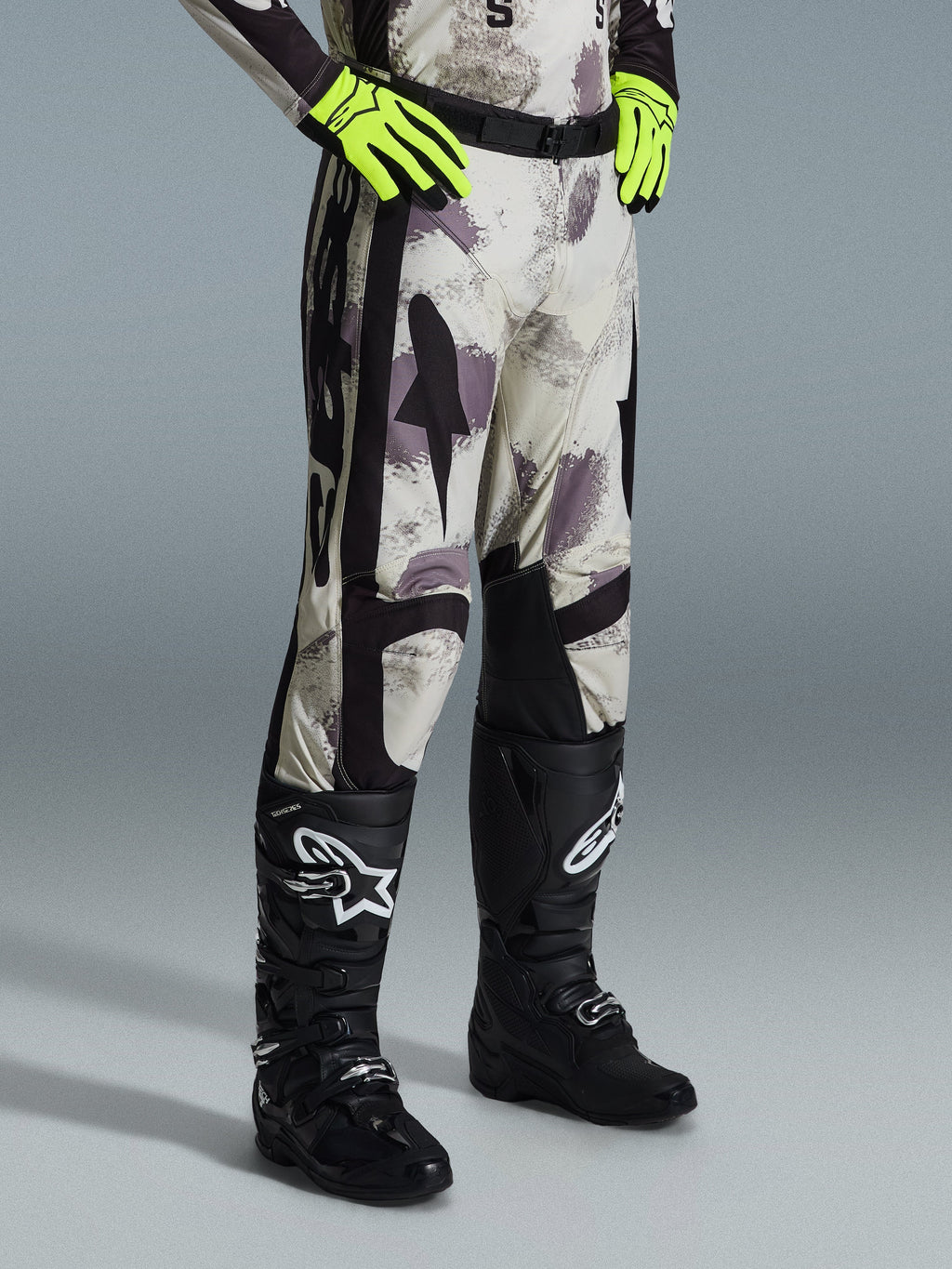 Alpinestars 2026 Racer Lahnd byxor, motocrossbyxor, Sand Camo, bärs med neongula handskar och svarta motocross-stövlar, med ett abstrakt kamouflagemönster med svarta sidopaneler, ergonomisk offroad-design
