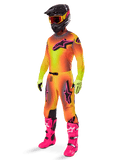 Motocrossförare klädd i 2025 Alpinestars Supertech Lipan-utrustningsset, gul och orange tröja och byxor med färgövergång och rosa detaljer, svart hjälm med gul-röda goggles, ljusgula handskar och starkrosa stövlar, koordinerad racingoutfit för terrängkörning