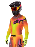 Motocrossförare i Alpinestars 2025 Supertech Lipan utrustningsset, gul och orange tröja med färgövergång, rosa och svart Astars-logotyp, neongula handskar, svart hjälm med röda goggles, professionell utrustning för terrängkörning