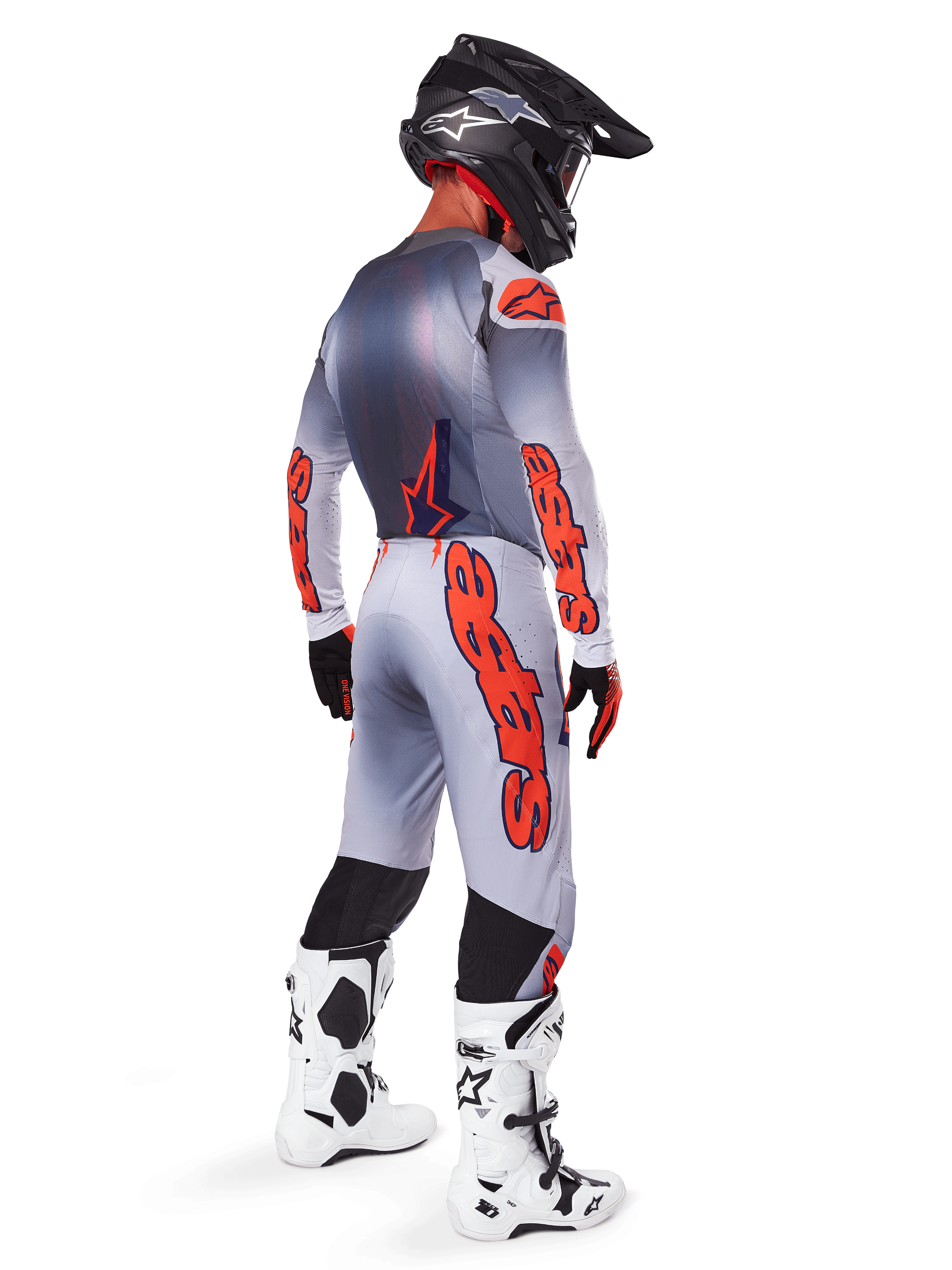 Motocross rider from a back-side profile wearing 2025 Supertech Lipan Jersey and matching pants in Gray and Orange Fluo, featuring bold orange Alpinestars branding on the sleeves and legs, paired with a black helmet and white boots, coordinated pro-level outfit for off-road racing