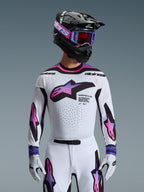 Alpinestars 2026 Supertech AFD Vista-utrustningsset, professionell motocrossutrustning, vit tröja och byxor med rosa och lila gradient-grafik, svart hjälm med lila goggles och vita handskar, atletisk race-passform för terrängkörning
