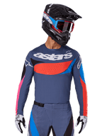 Alpinestars 2025 Techstar Dreem Jersey, motocrosströja, grå med blå, röda och rosa detaljer, med laserskurna perforeringar och stor logotyp på bröstet, bärs med matchande byxor och svart racinghjälm