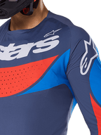 Närbild på Alpinestars 2025 Techstar Dreem jersey, marinblå med klarblå och orangea detaljer, vit Alpinestars-logotyp på bröstet och axeln, laserskurna perforeringar för ventilation