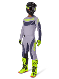 Alpinestars 2025 Techstar Dreem Gear Set, Motocross rider in full racing outfit, gray jersey and pants with dark gray patterns and neon yellow-green accents, matching black helmet, neon yellow-green gloves and boots, performance off-road gear
