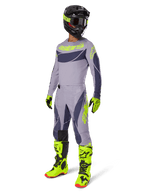Motocrossförare i 2025 Techstar Dreem Jersey i grått och mörkgrått med neongula detaljer, komplett racingutrustning inklusive matchande grå byxor, neongula stövlar och handskar och en svart hjälm, koordinerad offroad-prestandaoutfit