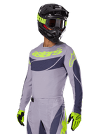 Motocrossförare iförd Alpinestars 2025 Techstar Dreem-tröja i grått och mörkgrått, med en neongul 'astars'-logotyp på bröstet, matchat med en matchande hjälm, goggles och handskar för en koordinerad look för terrängkörning