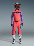 2026 Alpinestars Supertech Scenz utrustningsset, motocrossoutfit i livfull röd-orange och lila, tröja med svart 'astars'-logotyp, matchande byxor med lila stjärnlogotyper, färgstark racinghjälm och vita stövlar, professionell terrängutrustning