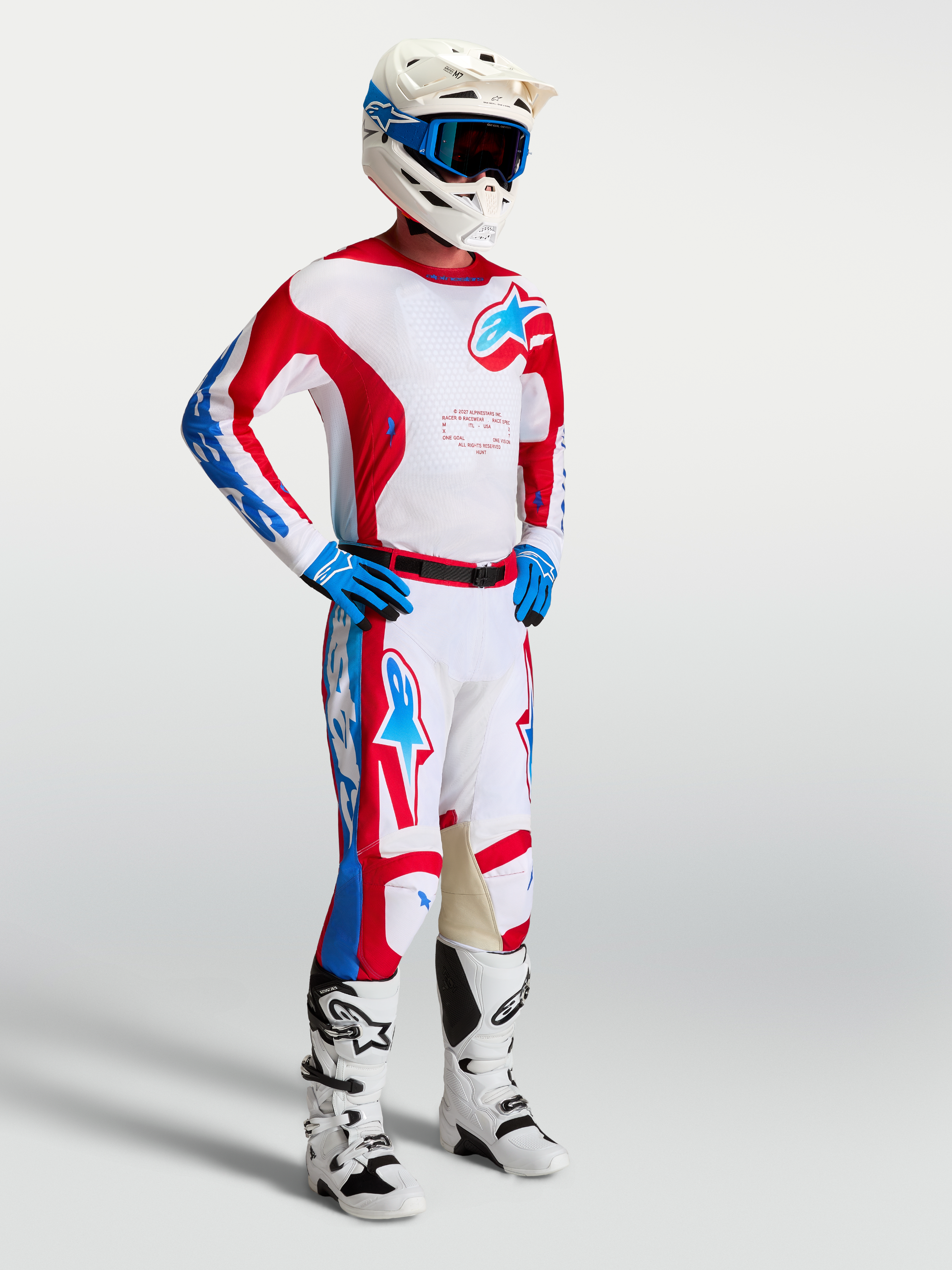 Alpinestars Racer Hunt gear set, röda och vita motocrossbyxor och tröja på modell för prestandainriktad terrängkörning.