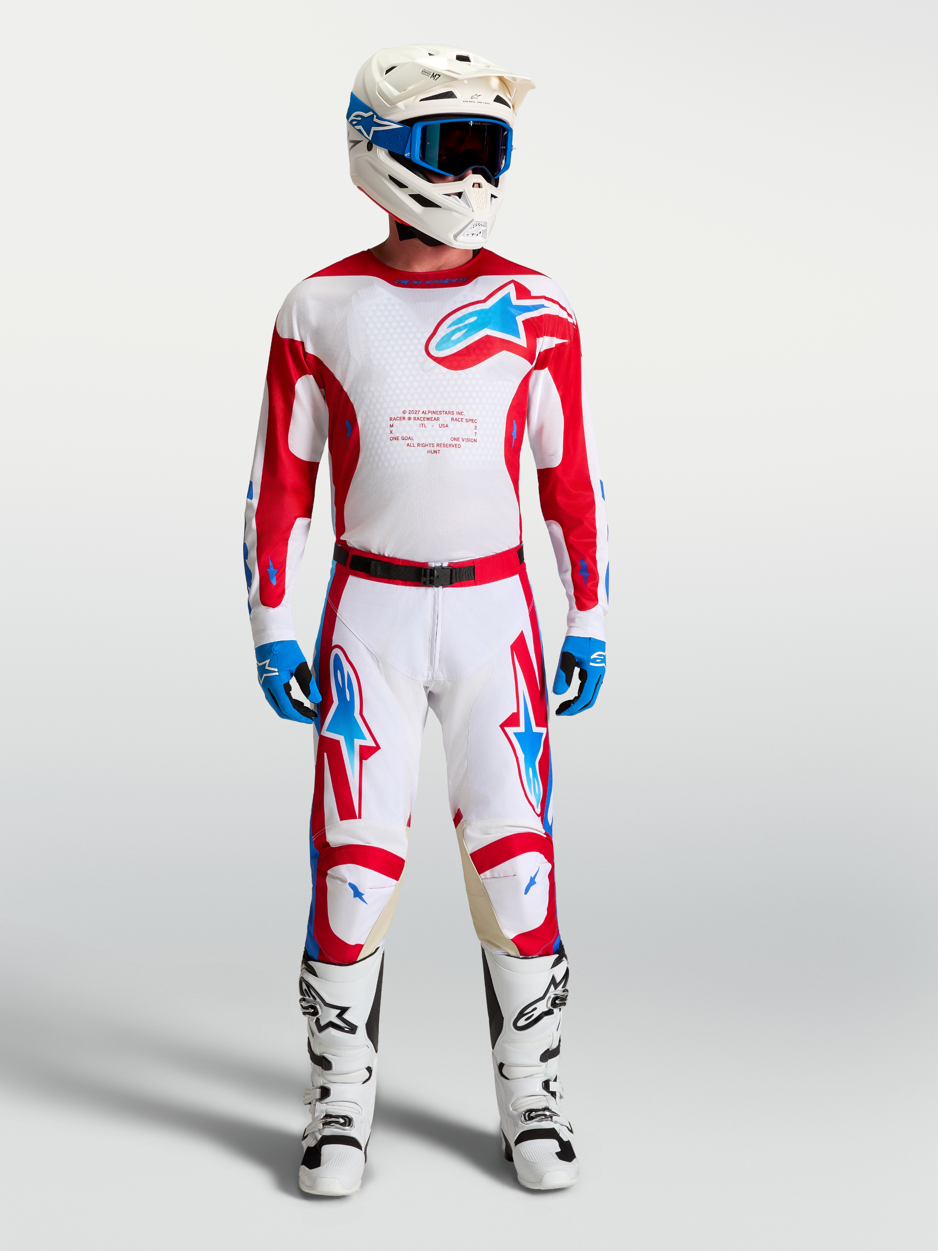 Alpinestars Racer Hunt motocrossutrustning, vit och röd med blå detaljer, förböjd ergonomisk passform, visas på modell.