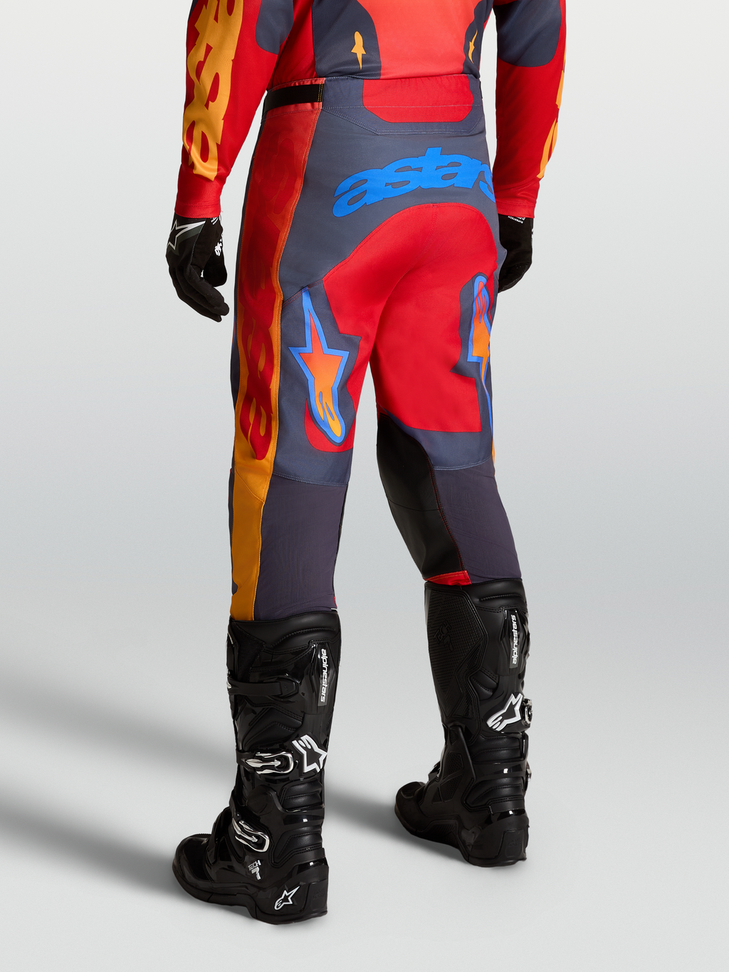 Alpinestars Racer Hunt byxor, motocrossbyxor i rött och grått med blå logotyp bakifrån, kombinerade med svarta Tech 7-stövlar för terräng
