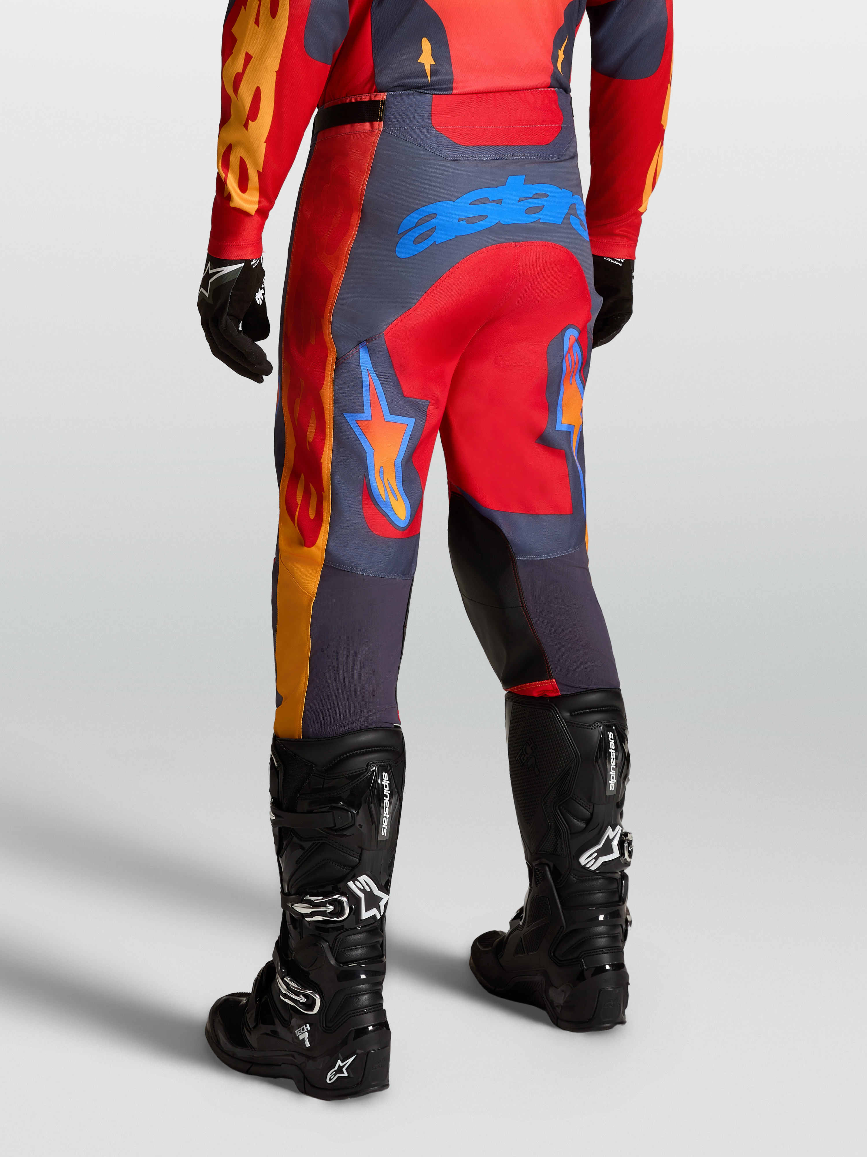 Alpinestars Racer Hunt byxor, motocrossbyxor i rött och grått med blå logotyp bakifrån, kombinerade med svarta Tech 7-stövlar för terräng