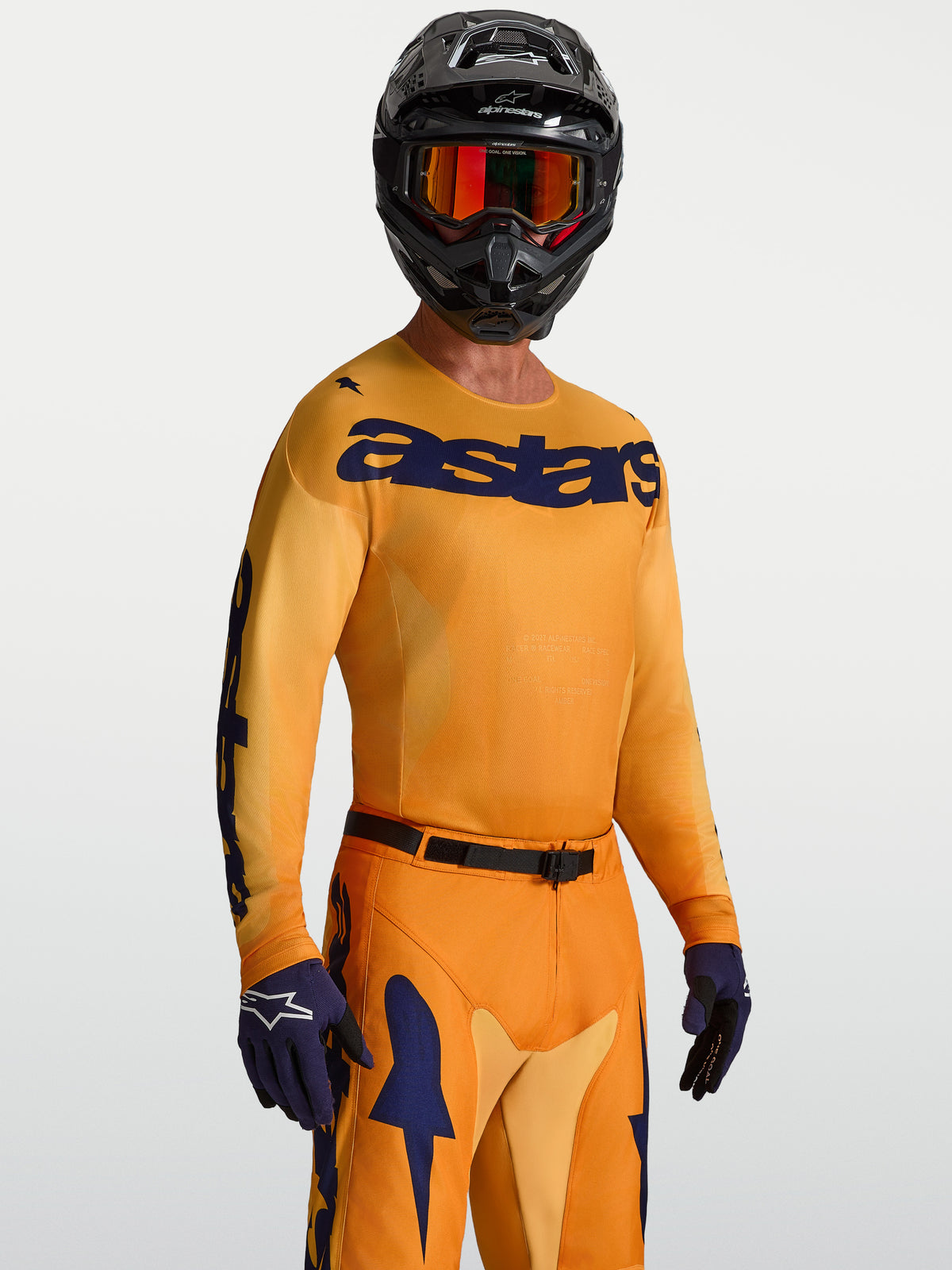 Alpinestars Racer Amber tröja, orange och djupblå motocrosströja i fukttransporterande polytyg, på modell med hjälm.