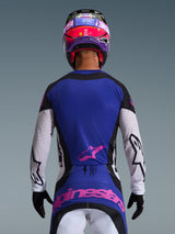 Motocrossförare sedd bakifrån iklädd 2026 Techstar Knif Jersey i Black Light Gray Purple, med en lila ryggpanel med rosa Alpinestars-logotyp, ljusgrå ärmar med svarta detaljer och laserskurna perforeringar, matchad med en lila och rosa hjälm och svarta handskar.