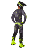 Bakifrån på en motocrossförare klädd i 2025 Racer Hollow Gear Set i Dark Camo Yellow Fluo, med en grå kamouflagemönstrad tröja med neongula detaljer, matchande motocrossbyxor med stor logotyp på sätet, neongula stövlar och en svart hjälm med gula goggles.