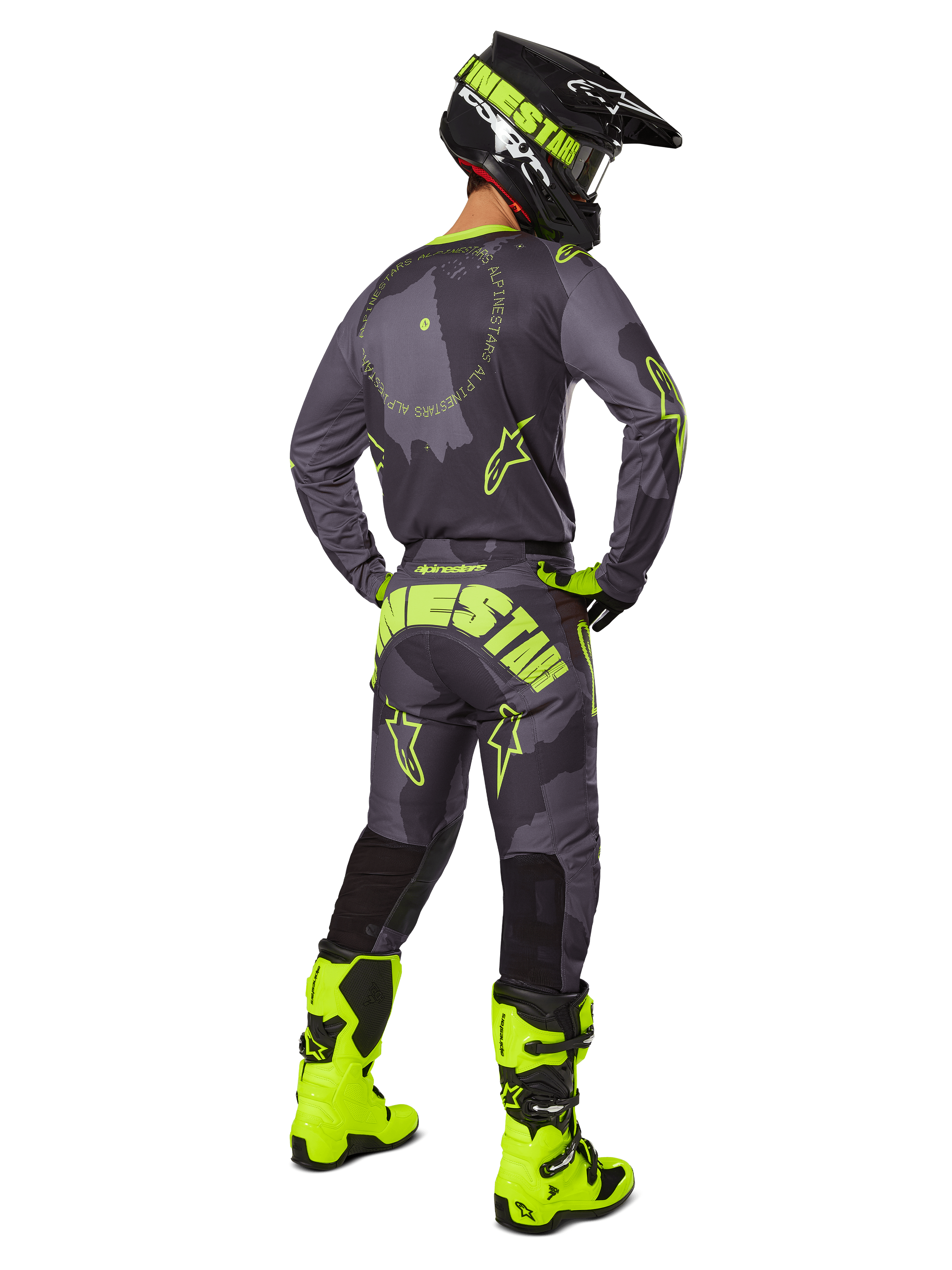 Bakifrån på en motocrossförare klädd i 2025 Racer Hollow Gear Set i Dark Camo Yellow Fluo, med en grå kamouflagemönstrad tröja med neongula detaljer, matchande motocrossbyxor med stor logotyp på sätet, neongula stövlar och en svart hjälm med gula goggles.