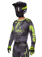 Alpinestars 2025 Racer Hollow-utrustningsset, motocrosströja och byxor i grått och neongult, bärs med matchande svart hjälm, goggles och handskar, med framträdande neongula Alpinestars-logotyper och stjärngrafik på en mönstrad grå bas, koordinerad professionell racinglook för terrängkörning
