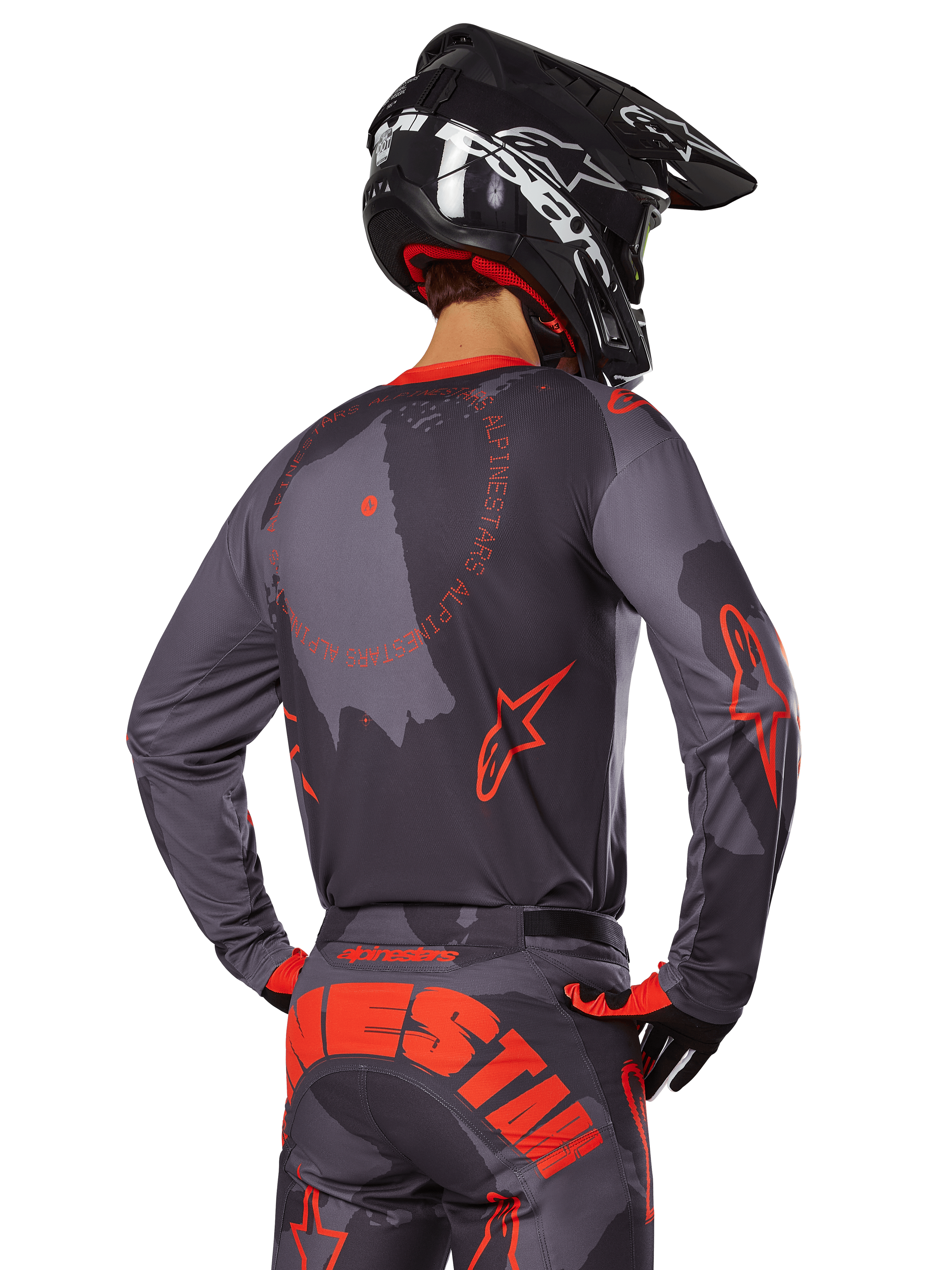 Alpinestars 2025 Racer Hollow Jersey, back view of a motocross rider in Gray Camo and Orange Fluo gear, featuring matching camo pants with large orange Alpinestars lettering and a black helmet, professional off-road apparel design