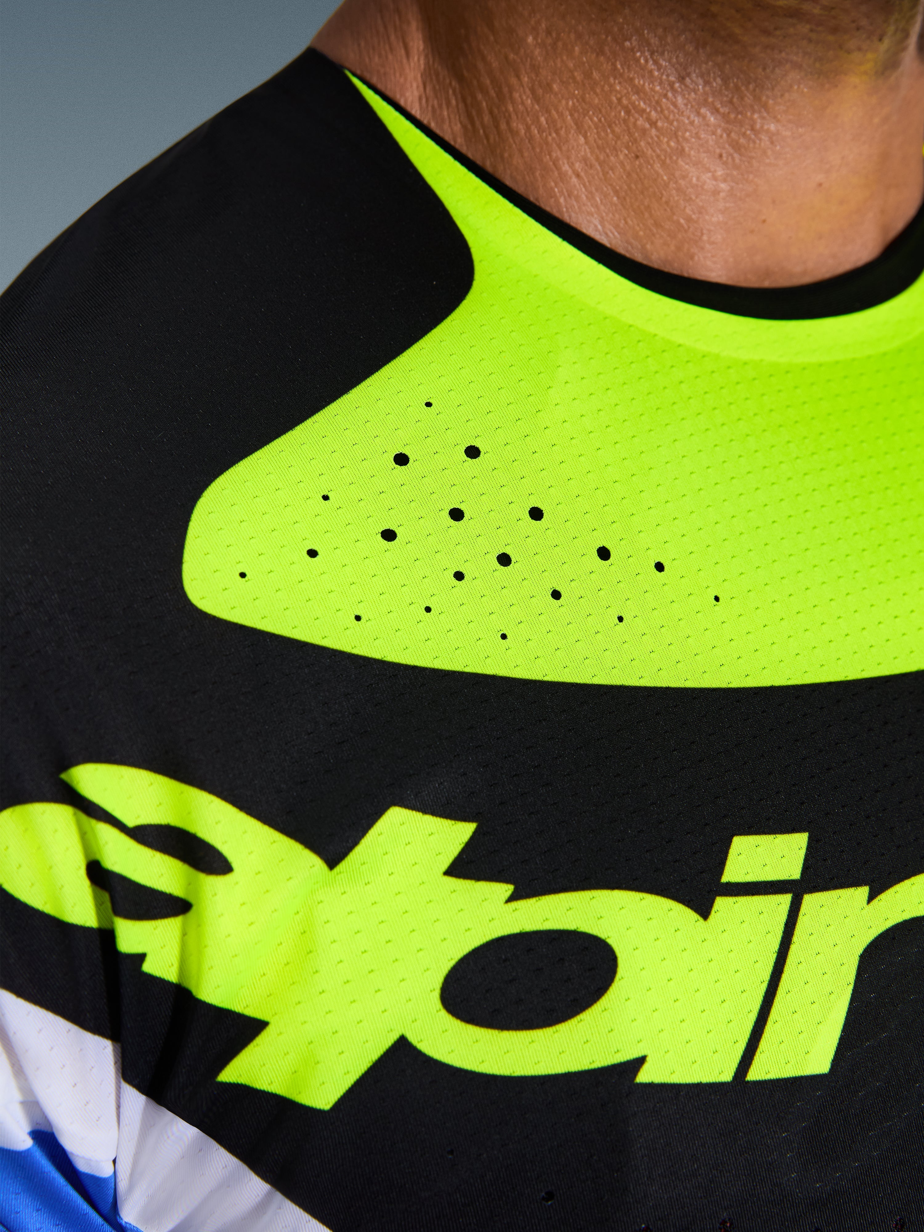 Närbild av Alpinestars 2026 Techstar Knif Jersey, svart och neongul, som framhäver laserskurna perforeringar för ventilation, sömlöst limmad krage och tekniskt fuktavledande material med gul logotyp.