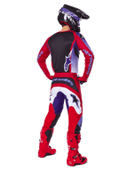 Motocross rider from behind wearing the Alpinestars 2025 Fluid Wurx Gear Set, Purple Bright Red jersey with black back panel, matching motocross pants with white and purple accents, bright red boots, and black helmet, professional off-road racing outfit