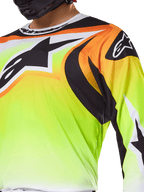 Alpinestars 2025 Fluid Wurx Jersey, Motocross Jersey, Fluorescent Yellow with Black and Orange graphics, featuring a large black Alpinestars logo on the chest and shoulder, worn by a rider with a black helmet.