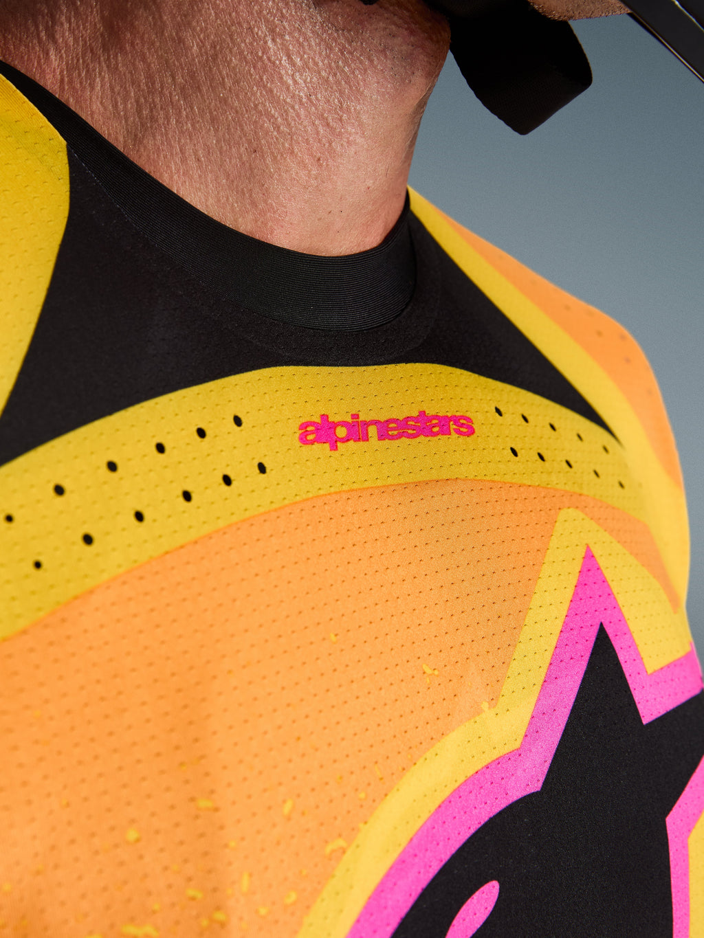 Alpinestars 2026 Techstar Nomur-tröja, motocrosströja, orange, gul och rosa, närbild på bröst och krage, med laserskuren ventilation, rosa logotyp och ventilerande meshtyg
