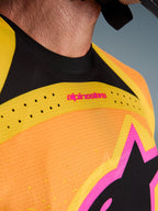 Alpinestars 2026 Techstar Nomur-tröja, motocrosströja, orange, gul och rosa, närbild på bröst och krage, med laserskuren ventilation, rosa logotyp och ventilerande meshtyg