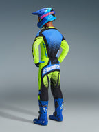 Motocrossförare sedd bakifrån bärande komplett racingutrustning, 2026 Techstar Nomur-tröja i gul fluo och blått, matchande gula och svarta byxor med blå detaljer, blå hjälm med rosa Alpinestars-logotyp och blå stövlar, studiobild som framhäver ryggdesignen och atletisk passform.