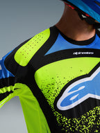 Alpinestars 2026 Techstar Nomur tröja, motocrosströja, neon gul, mörkblå och UCLA-blå, närbild på bröst och axel som visar laserskurna perforeringar för ventilation och Alpinestars-logotypen, prestandautrustning för terrängkörning