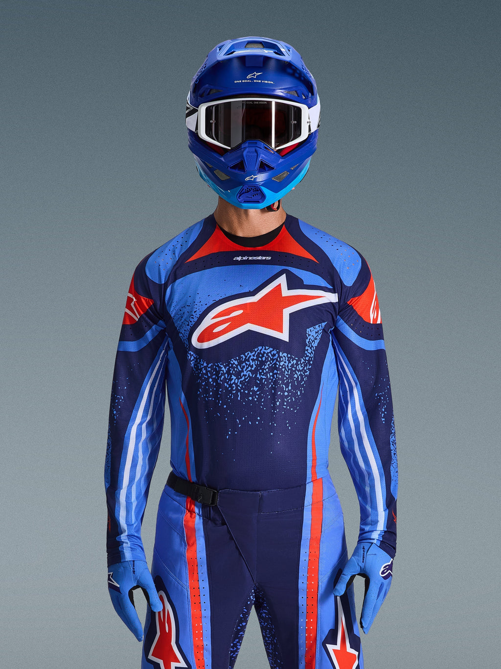 Motocrossförare iklädd Alpinestars 2026 Techstar Nomur Jersey i Dark Navy, orange och UCLA Blue, matchande byxor och blå handskar, blå hjälm med vita goggles, stor röd och vit Alpinestars-logotyp på bröstet, koordinerad prestandautrustning för terrängkörning.
