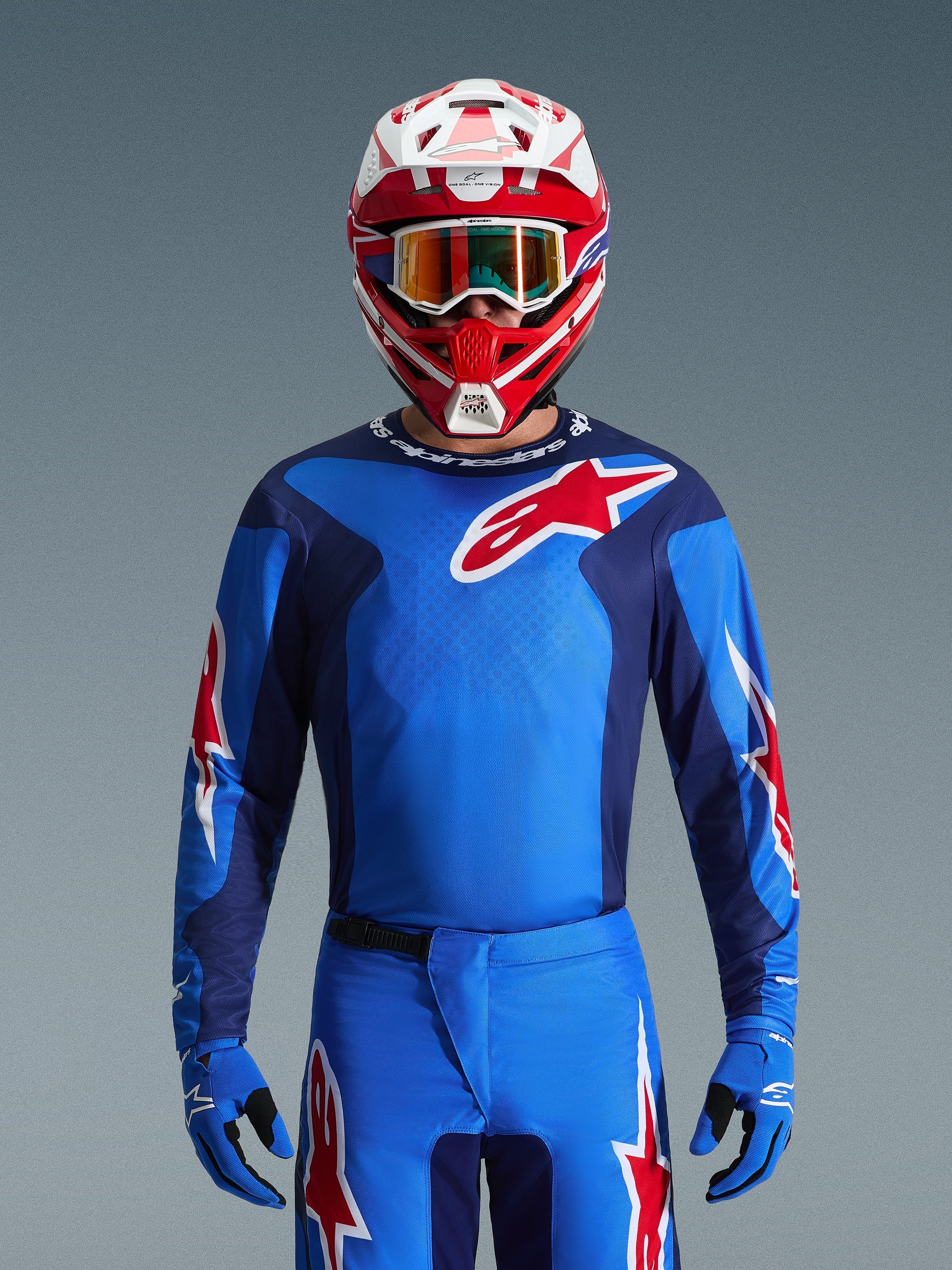 Alpinestars 2026 Fluid Grid tröja, blå och röd motocrosströja, bärs med matchande byxor och en röd och vit hjälm, med framträdande röda stjärnlogotyper och en atletisk passform designad för prestanda vid offroad-racing