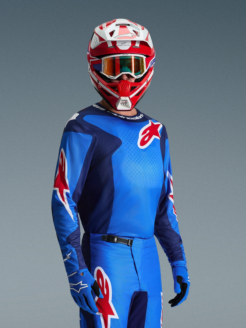 Motocrossförare som bär Alpinestars 2026 Fluid Grid-tröja i blått och rött, med röda Alpinestars-stjärnlogotyper, matchad med tillhörande blå byxor, blå handskar och en röd och vit hjälm med goggles