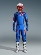 Motocrossförare iklädd Alpinestars 2026 Fluid Grid-tröja i blått och rött, matchande blå byxor med vita och röda stjärnlogotyper, röd och vit hjälm med spegelglasgoggles, blå handskar och vita och svarta racingstövlar, komplett off-road-utrustning.
