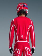 Motocrossförare sedd bakifrån i Alpinestars 2026 Fluid Apex-tröja i rött och vitt med geometriska vita mönster, stylad med matchande motocrossbyxor och en röd hjälm, komplett racingutrustning för offroad-prestanda.