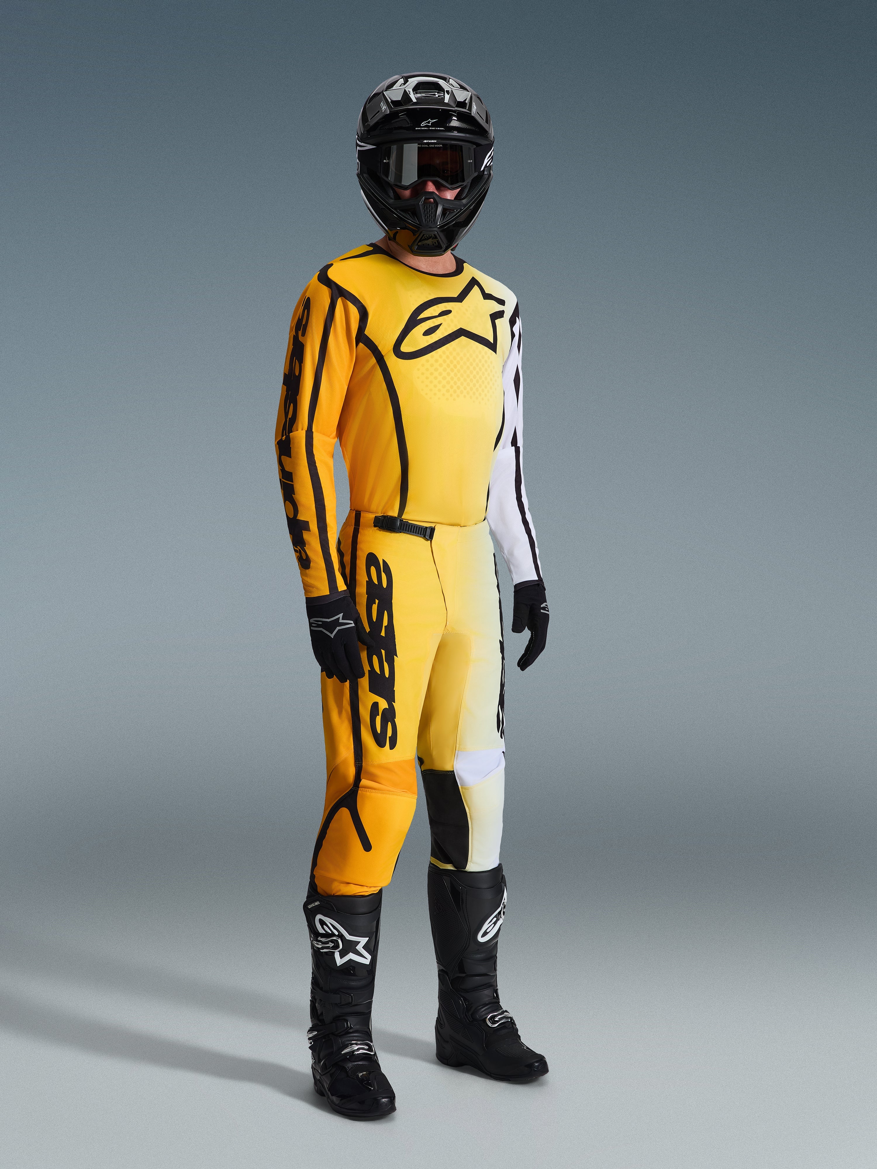 Motocrossförare iklädd Alpinestars 2026 Fluid Apex-tröja i gult och svart, med en gradientdesign från gult till vitt och en stor svart logotyp på bröstet, matchande byxor, svart hjälm och svarta stövlar, komplett racingutrustning för off-road motocross.
