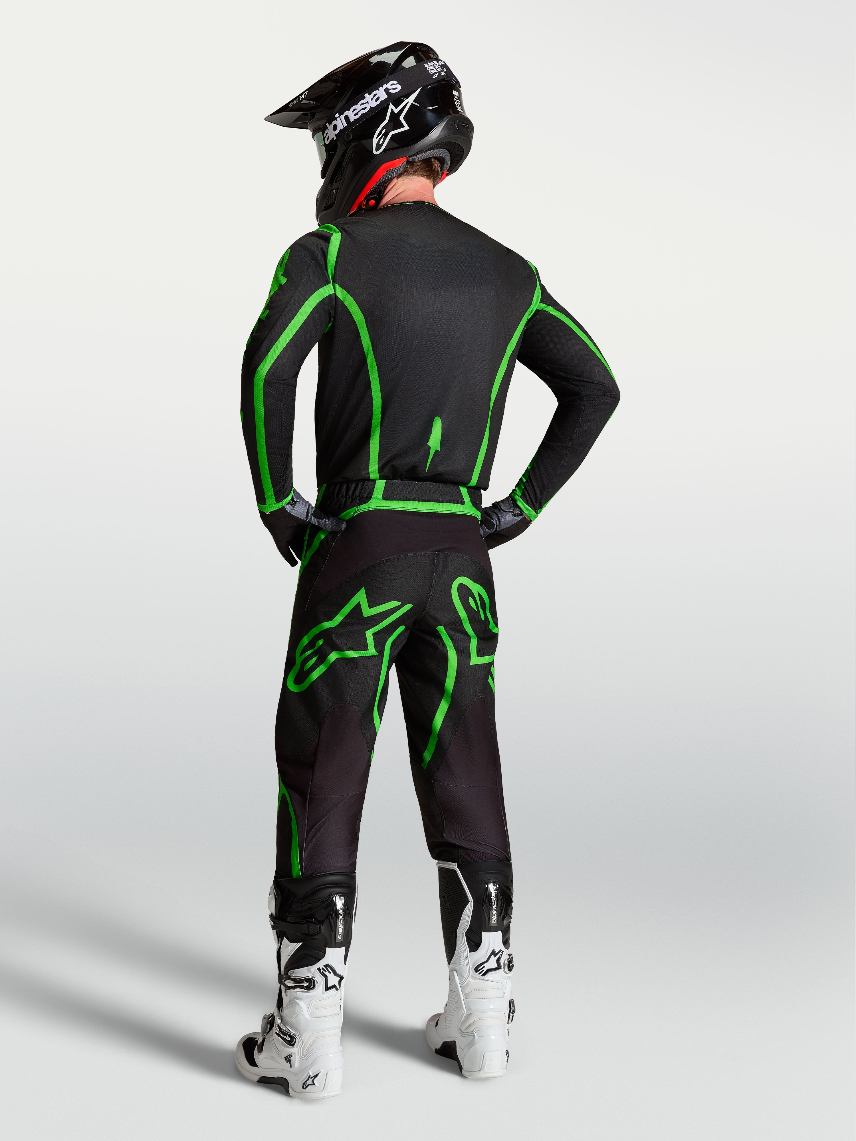 Alpinestars Fluid Apex V2 tröja, svart och neongrön motocrosströja, vy bakifrån på modell med matchande byxor och hjälm.
