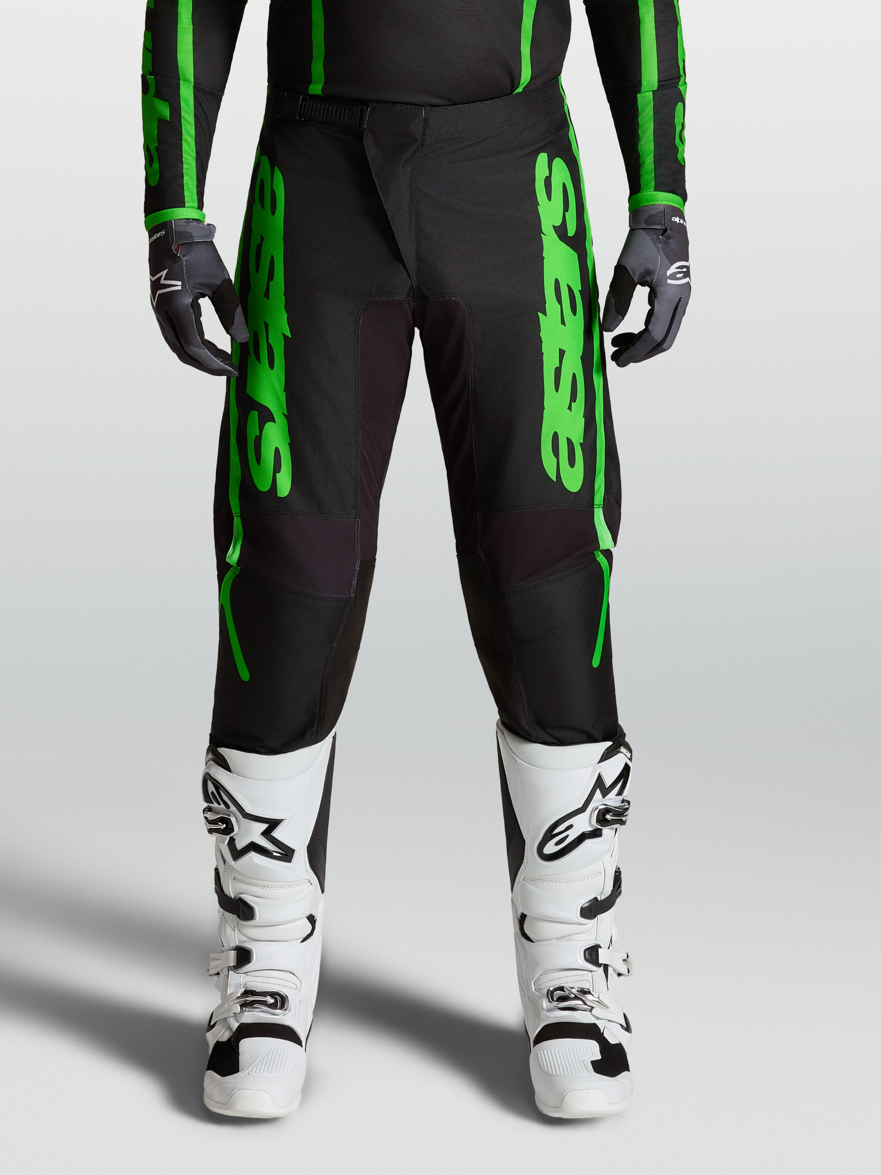 Alpinestars 2027 Fluid Apex V2 byxor, herrmotocrossbyxor i grönt och svart med förstärkta knän och vita stövlar.