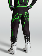 Alpinestars Fluid Apex V2 byxor, motocrossbyxor herr i svart och grön fluo, vy bakifrån på modell med vita off-road-stövlar.