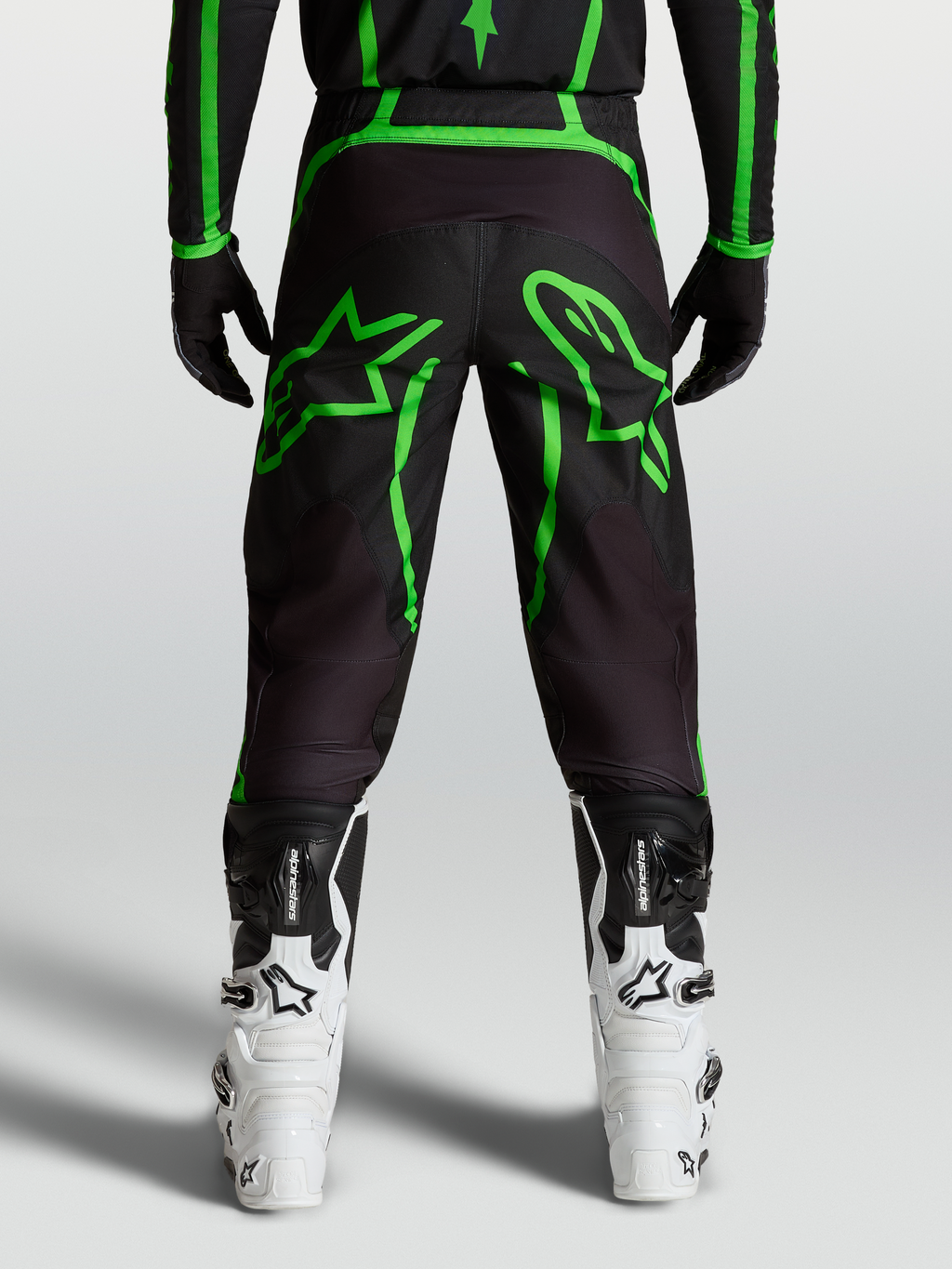 Alpinestars Fluid Apex V2 byxor, svarta och gröna motocrossbyxor för herr med stor stjärngrafik, vy bakifrån på modell.